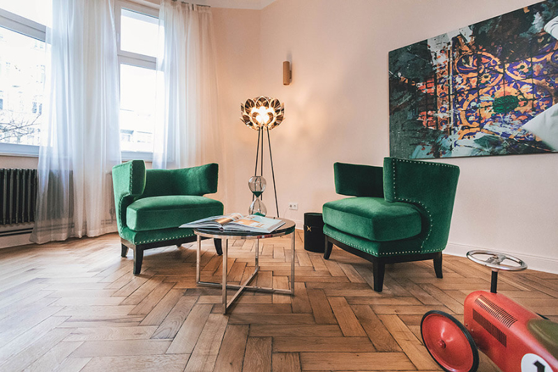 the best interior designers of germany, carlo berlin living space with a vintage center table and 2 green armchairs